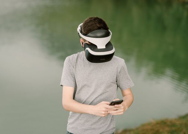 Young teenager with virtual reality glasses and smart phone outdoors