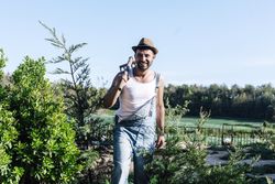 Smiling young farmer man standing in the garden while looking in the distance