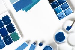 Blue paint palette and tubes on bright background with copy space