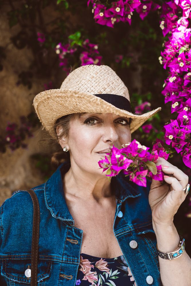 Woman standing near a wall with flower shrubs