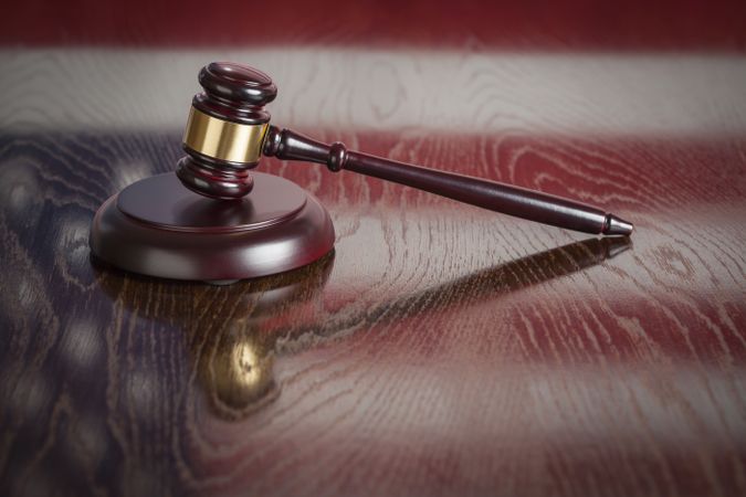 Wooden Gavel Resting on Flag Reflecting Table