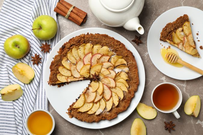Composition with apple pie and ingredients on gray background, top view