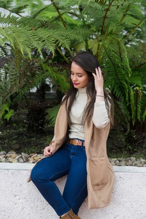 Woman in warm clothes sitting on stone fence