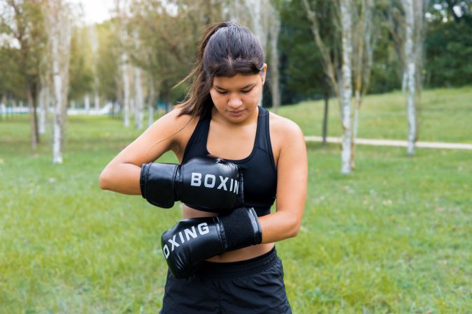 Boxer woman putting on boxing gloves in an outdoor sparring training