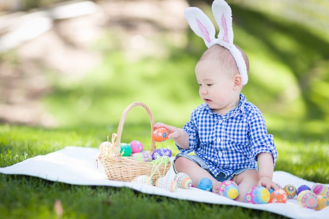 Baby Boy Outside In Rabbit Ears Playing with Easter Eggs