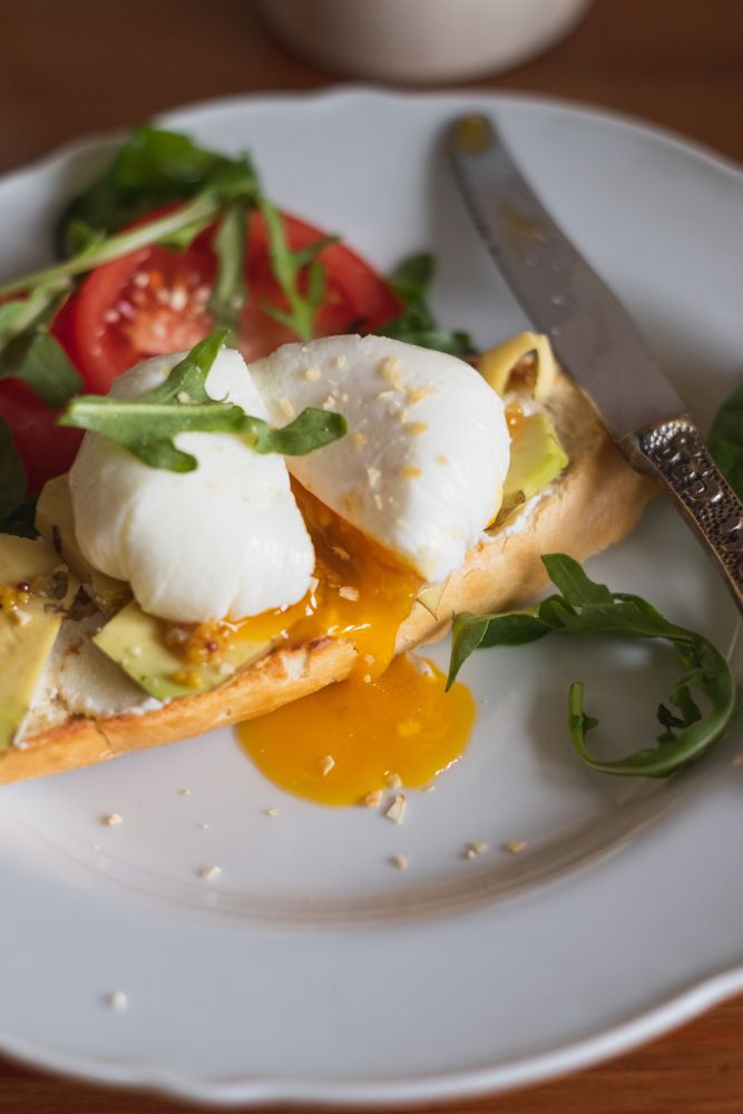 Healthy avocado toast with poached egg, tomato and arugula