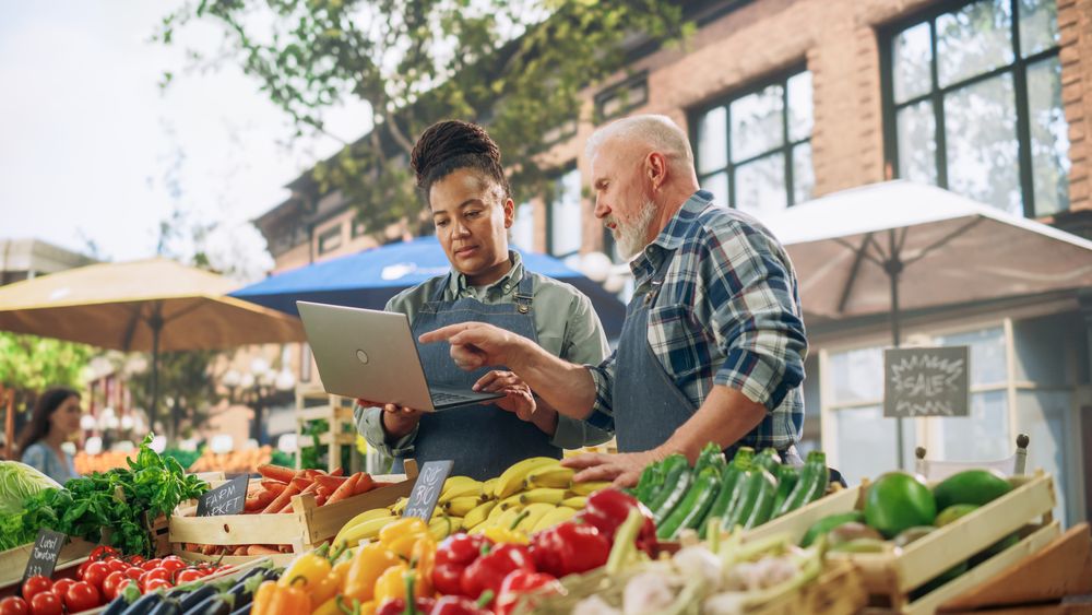 Female and Male Business Partners Managing a Successful Organic Food Stall at a Farmers Market.