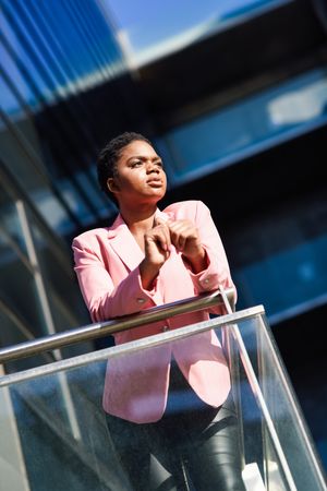 Woman in smart business attire leaning outside building looking in the distant