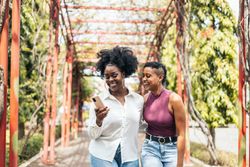 Happy women taking selfies with smartphone walking in the park