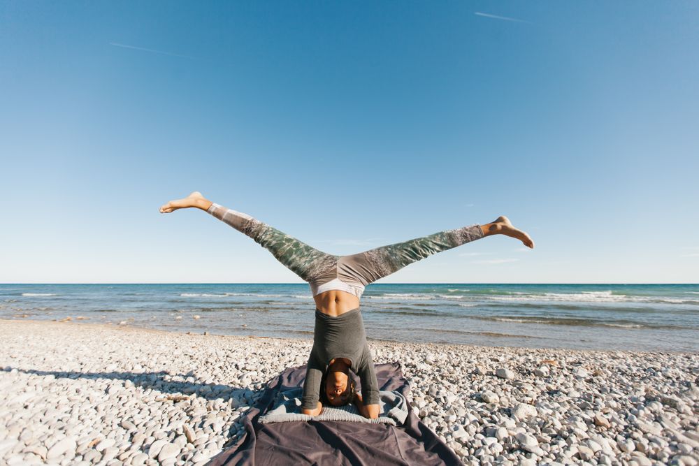 Sportive woman performing yoga posture in the beach
