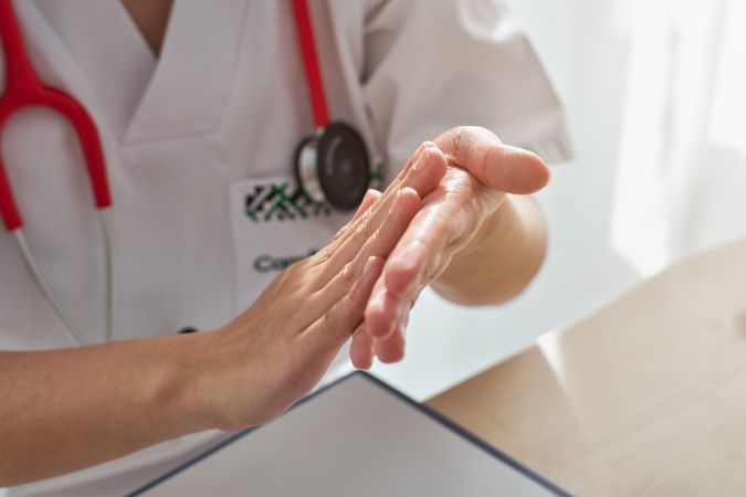 Unrecognizable doctor cleaning hands with antiseptic