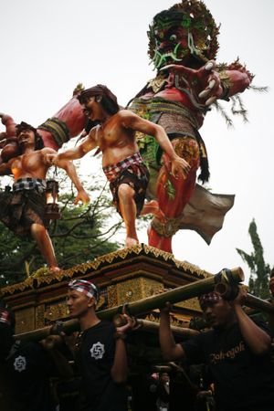Red statue being carried by men during Hindu prayer ceremony
