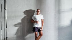 Man standing against the wall with water after exercising with water bottle