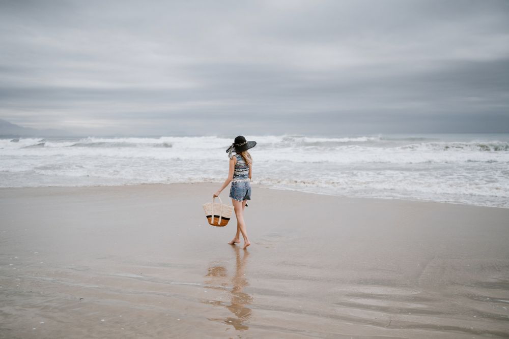 Young female walking barefoot on sandy beach