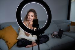 Smiling focused female applying lipstick while recording video o