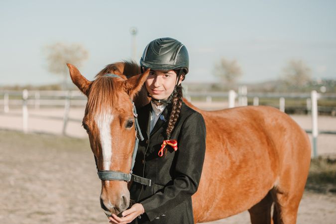 Woman in jockey outfit standing with horse