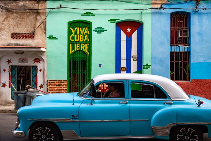 Side view of man riding a blue vintage car in Havana, Cuba