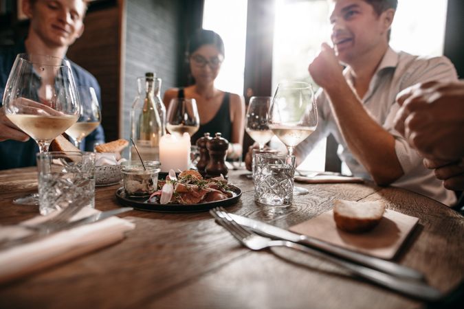 Group of friends meeting at cafe with glasses of wine on table