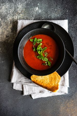 Gazpacho soup served in dark bowl with toast