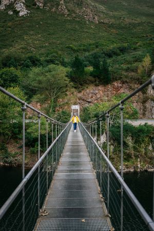 Cheerful female tourist standing on hanging bridge in summer