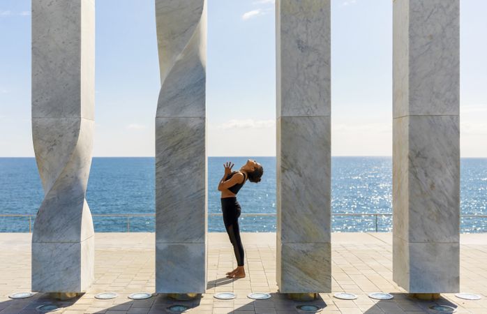 Side view of female doing yoga between sculpture by the sea