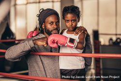 Girl in boxing gloves standing with her coach fist bumping 5qDQq0