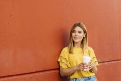 Young blonde woman drinking takeaway coffee