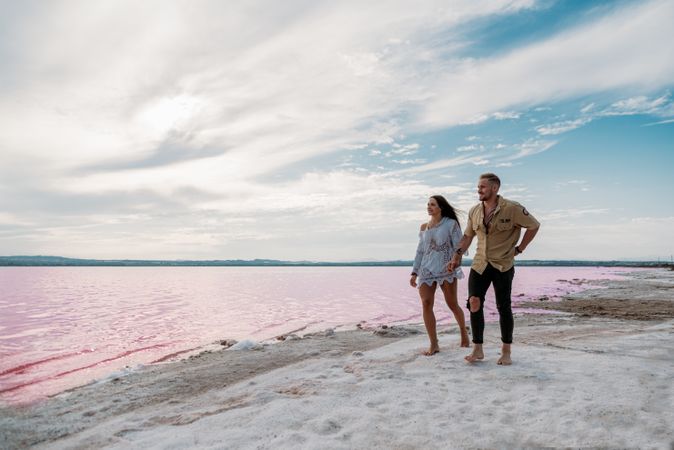 adorable couple walking on an amazing beach with pink water