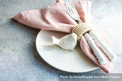Easter table setting on concrete background with bird figurine and pink napkin 4BavYX