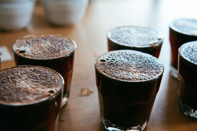 Top view of multiple glasses of coffee lined up in counter for coffee tasting