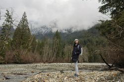 Young woman in the mountains standing near a stream