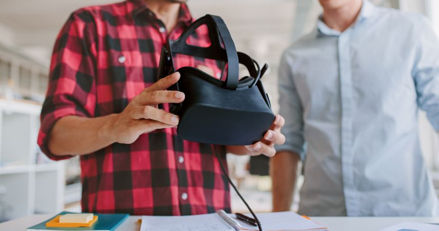 Cropped shot of two young men testing virtual reality headset in office