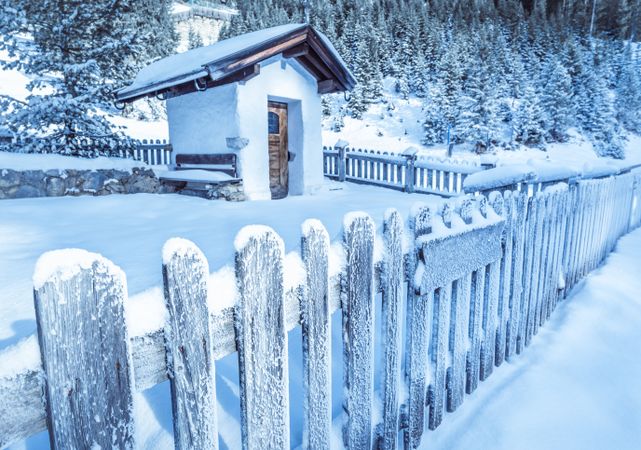 Frozen wooden fence and rustic chapel