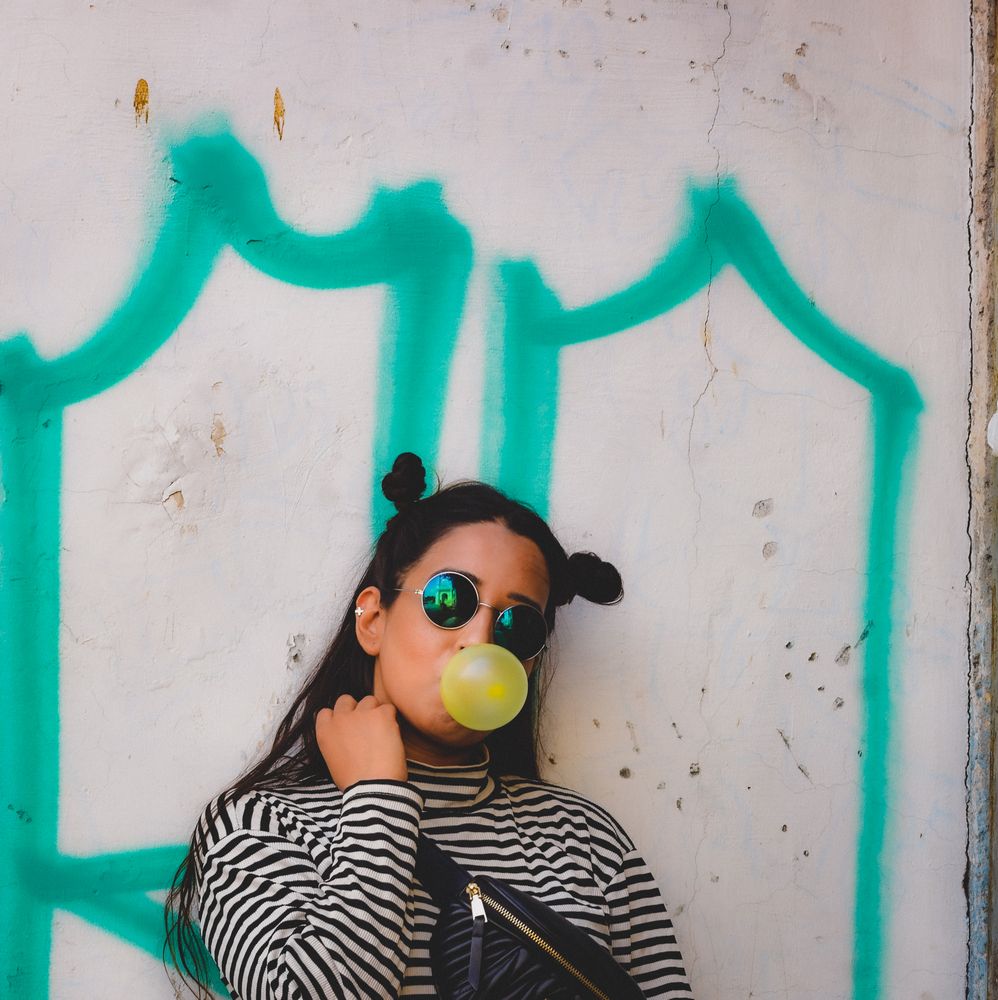 Woman blowing yellow chewing wearing sunglasses