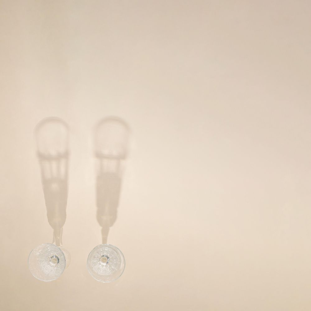 Top view of two champagne glasses on beige table with copy space