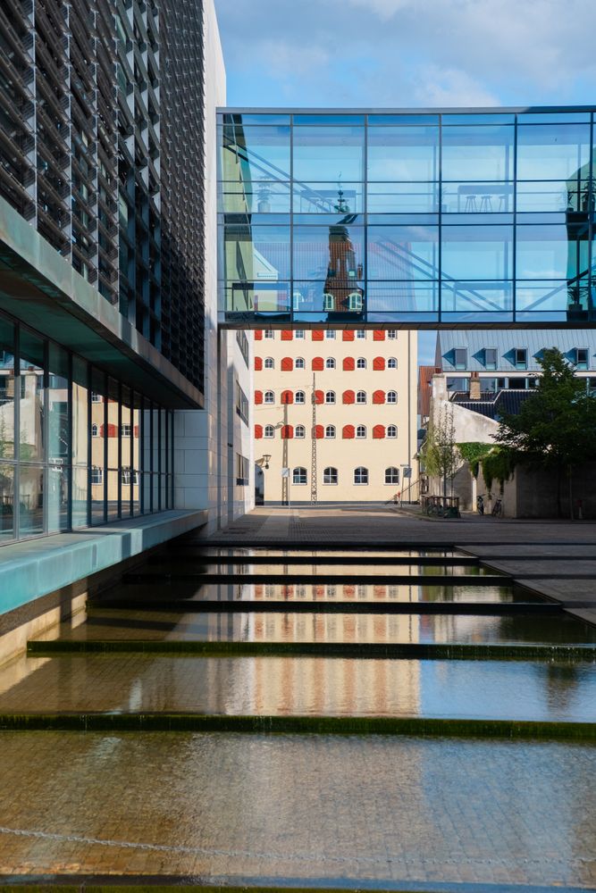 Walkway of corporate glass building with water feature underneath