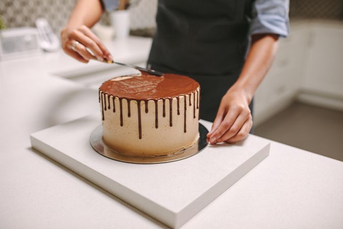 Cropped shot of baker smoothing top of cake