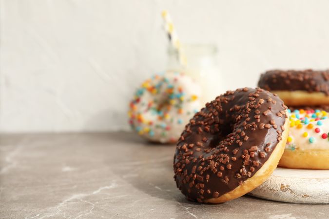 Jar of milk and tasty donuts on gray table