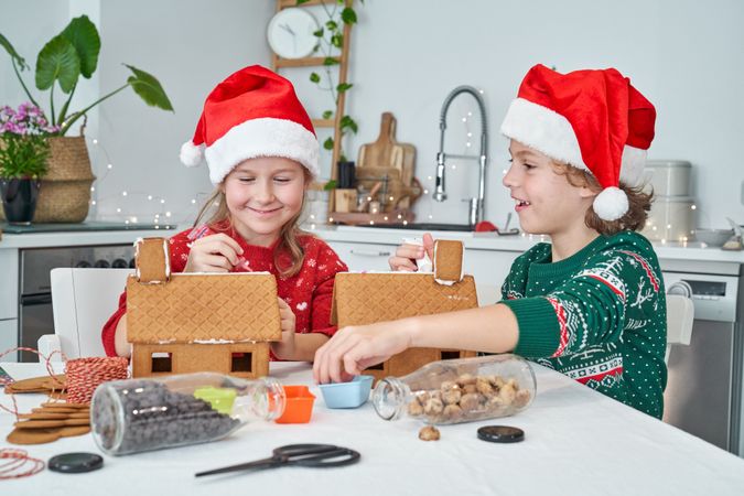 Content children applying icing on gingerbread houses