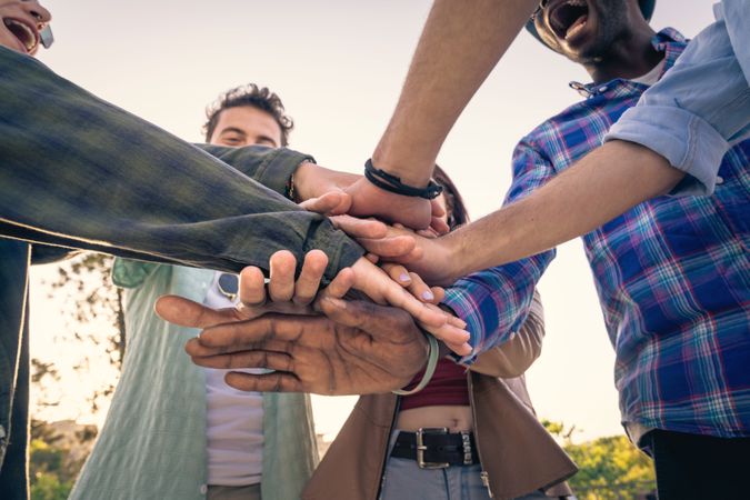 Close-up of diverse hands linked together in a circle, showing unity and trust.