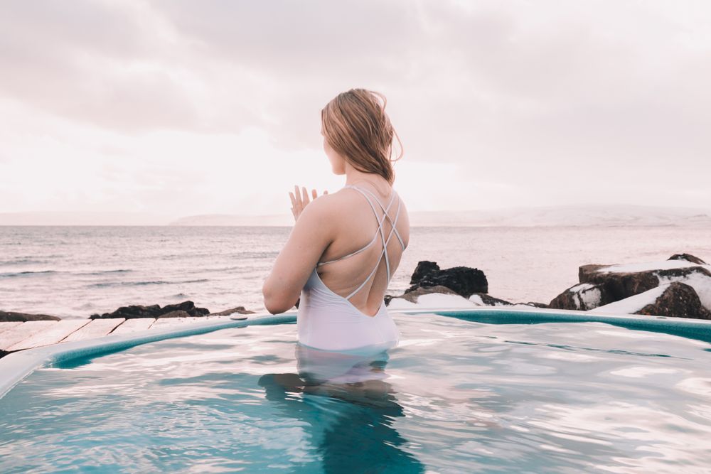 Woman sitting in pool near stones
