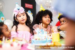 Diverse group of children at a birthday party with cake, balloons and candles 41rygb