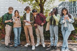 Multi-ethnic group of students checking their phones on campus