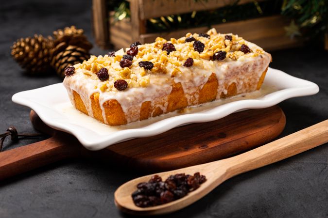 Fruit cake served on wooden board with spoon and pine cone