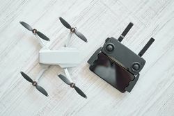 New modern drone with remote control panel placed on floor