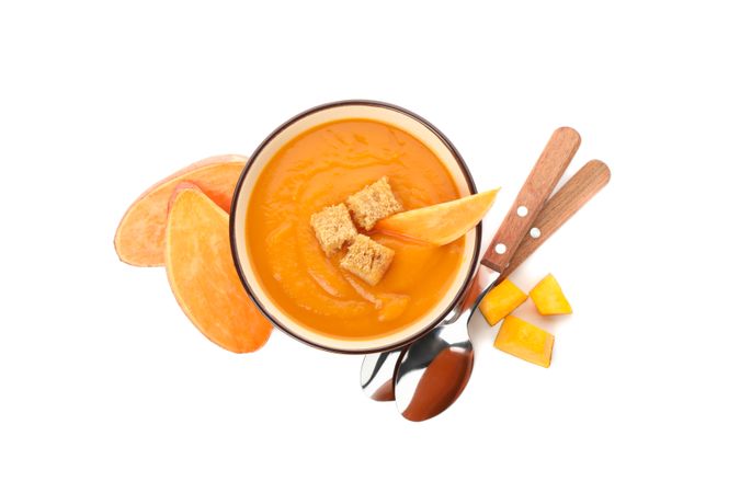 Looking down at sweet potato soup with croutons and spoons