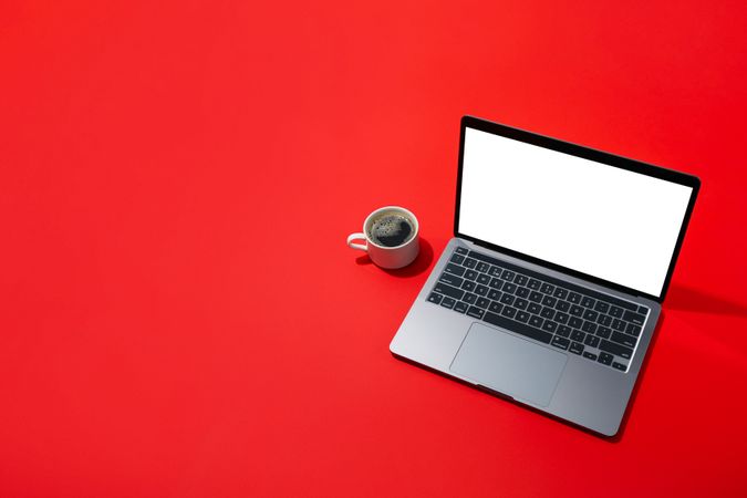 Top view of laptop keyboard on red table with coffee with copy space