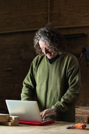 Smiling male woodworker using laptop for work