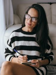 Woman writing in notebook near couch