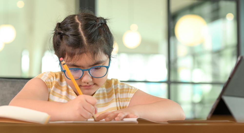 Cropped shot of Asian girl with glasses studying at home